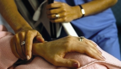 Immagine di una mano di una malata di SLA che è tenuta dalla mano di un'infermiera